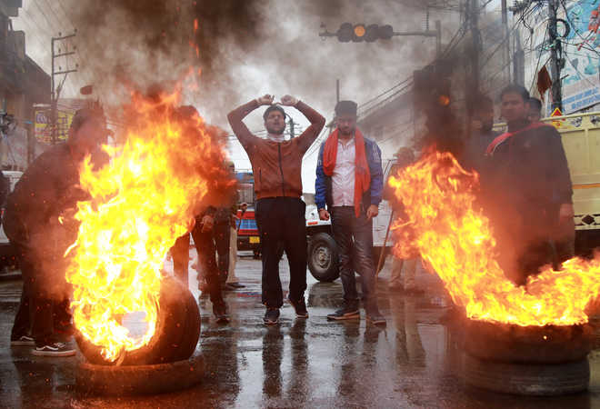 Demonstrators shout slogans next to burning tyres during a protest in Kishtwar town, in Jammu